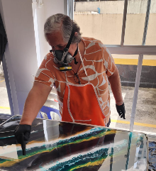 Aluno trabalhando em painel colorido de resina epóxi durante aula prática